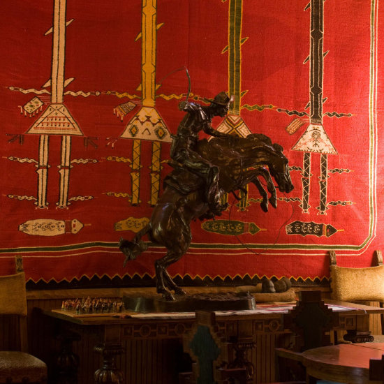 A bronze statue of a cowboy in front of a Navajo rug
