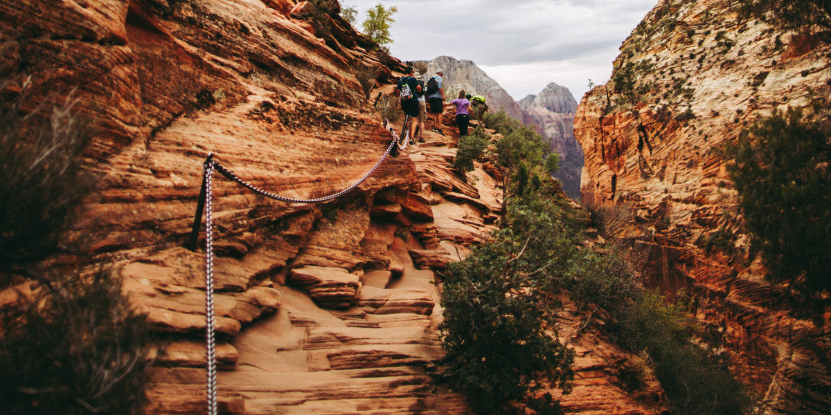 Hikers follow chains as they hike over red rock