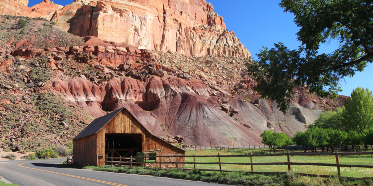 A barn with red rock cliffs in the background