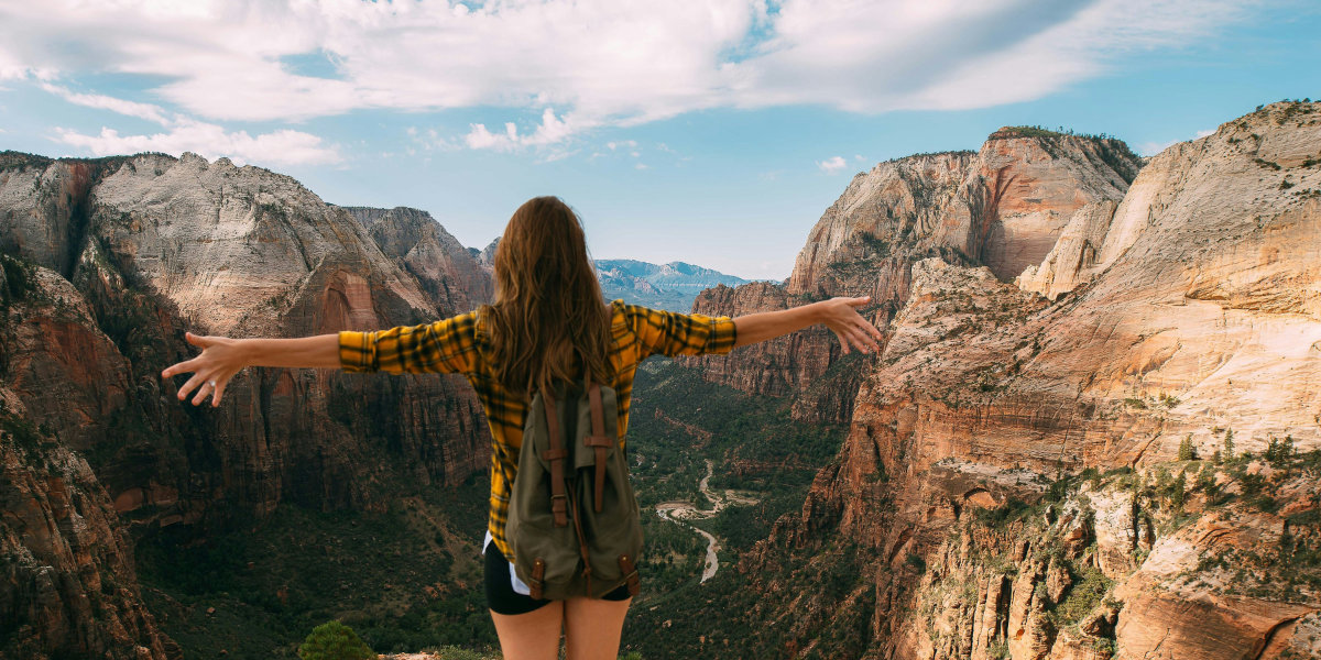 A woman stands at the top of Angels Landing in Zion